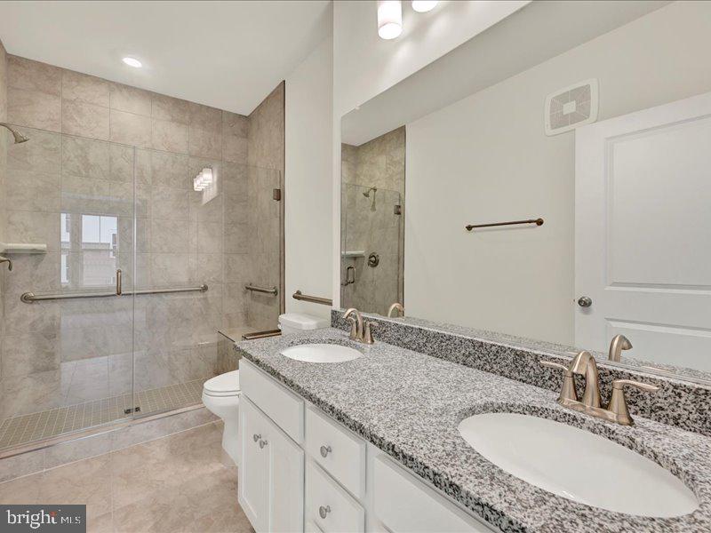4003 Seaside Alder Road, Unit 307 HOLLY Bowie, MD 20720 - Photo 21 of 28 a bathroom with a granite countertop double vanity sink a mirror and a shower
