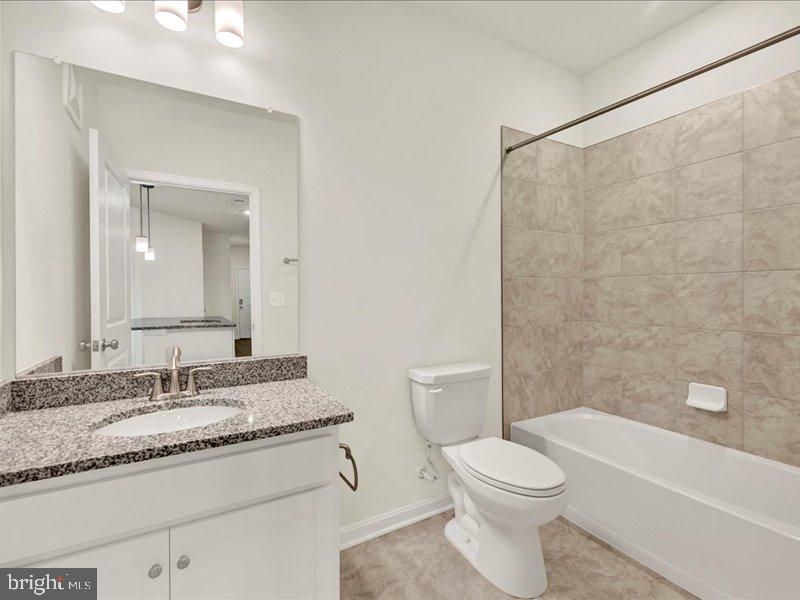 4003 Seaside Alder Road, Unit 307 HOLLY Bowie, MD 20720 - Photo 23 of 28 a bathroom with a granite countertop sink toilet and shower