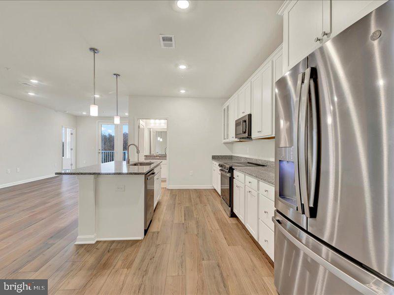 4003 Seaside Alder Road, Unit 307 HOLLY Bowie, MD 20720 - Photo 5 of 28 a kitchen with stainless steel appliances a refrigerator sink and wooden floor