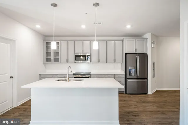 a kitchen with stainless steel appliances granite countertop a refrigerator a sink a stove and white cabinets