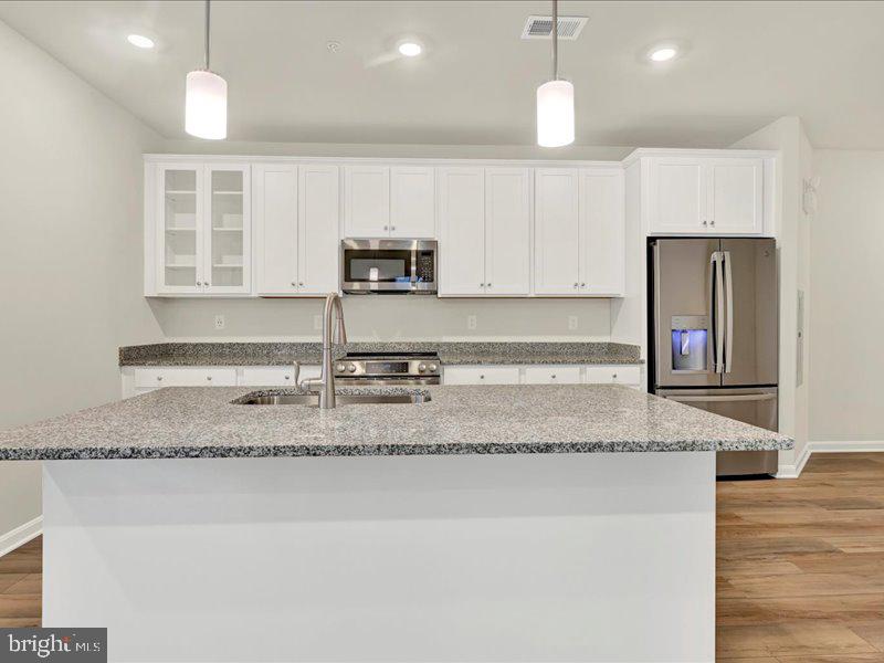 4003 Seaside Alder Road, Unit 307 HOLLY Bowie, MD 20720 - Photo 6 of 28 a kitchen with kitchen island granite countertop a sink a counter top space appliances and cabinets