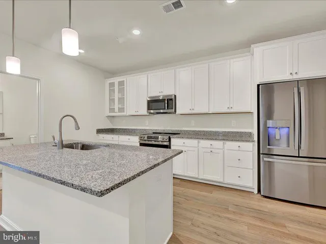 a kitchen with granite countertop white cabinets and stainless steel appliances