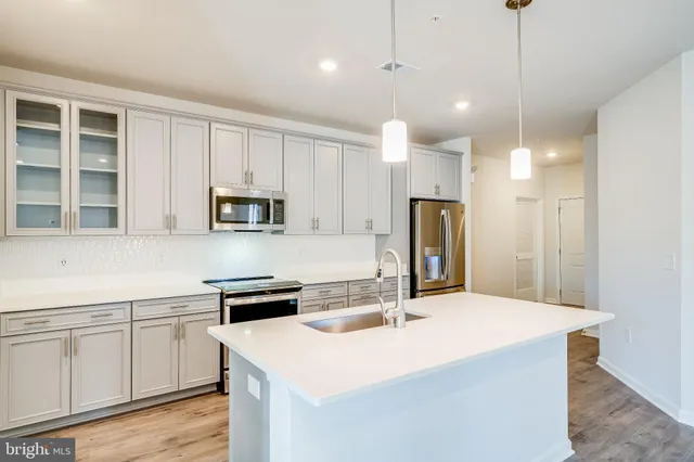 a kitchen with a sink a stove a refrigerator and white cabinets