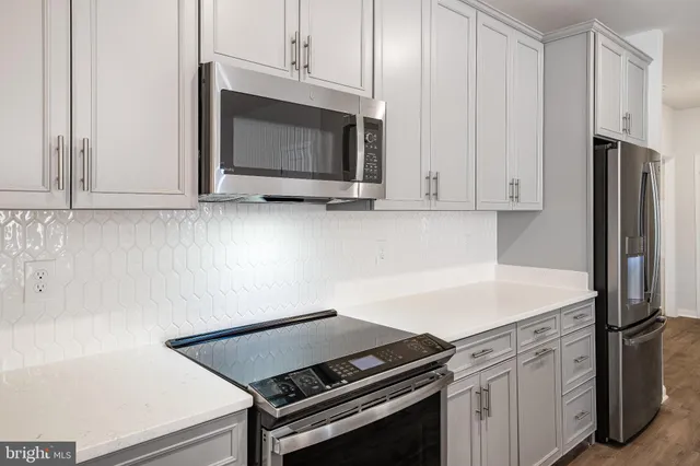 a kitchen with granite countertop white cabinets and stainless steel appliances