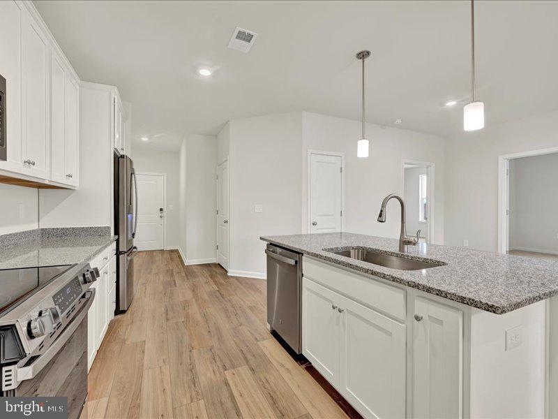4003 Seaside Alder Road, Unit 307 HOLLY Bowie, MD 20720 - Photo 8 of 28 a kitchen with a sink stove and white cabinets with wooden floor