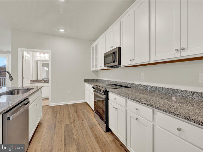 4003 Seaside Alder Road, Unit 307 HOLLY Bowie, MD 20720 - Photo 9 of 28 a kitchen with granite countertop wooden cabinets stainless steel appliances and a counter space
