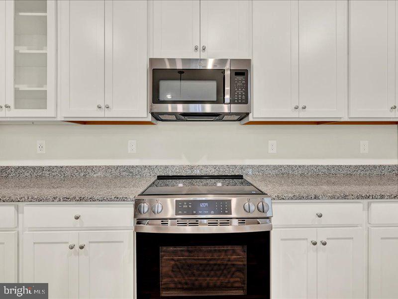 4003 Seaside Alder Road, Unit 307 HOLLY Bowie, MD 20720 - Photo 10 of 28 a kitchen with granite countertop a stove and a white cabinets