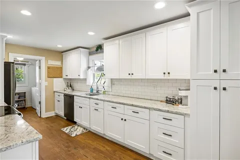 a kitchen with granite countertop white cabinets sink and stainless steel appliances