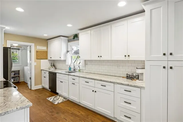 a kitchen with granite countertop white cabinets sink and stainless steel appliances