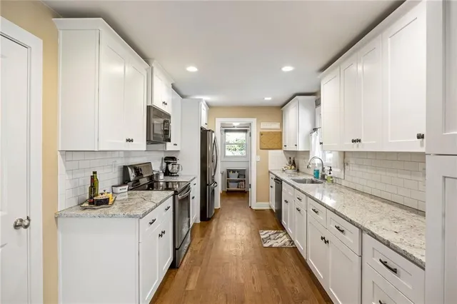 a large kitchen with stainless steel appliances granite countertop a lot of counter space and wooden floors