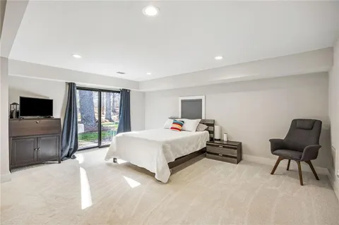 a spacious bedroom with a bed and a chair with the screen