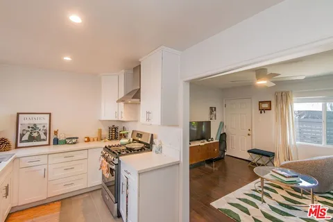 a kitchen that has a lot of white cabinets and wooden floor