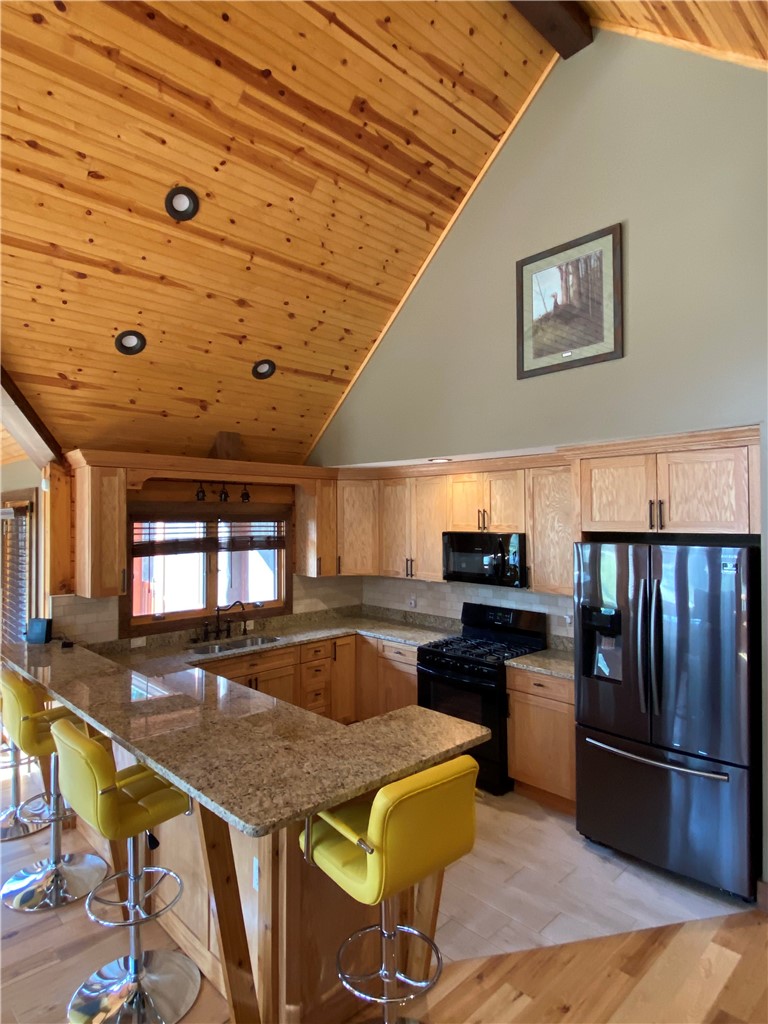 128 McAlister Road West Union, SC 29696 - Photo 17 of 40 A rustic-inspired kitchen with a vaulted wood-paneled ceiling and a practical U-shaped island with bar seating.