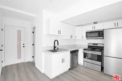 a kitchen with stainless steel appliances granite countertop a sink a stove a refrigerator and cabinets