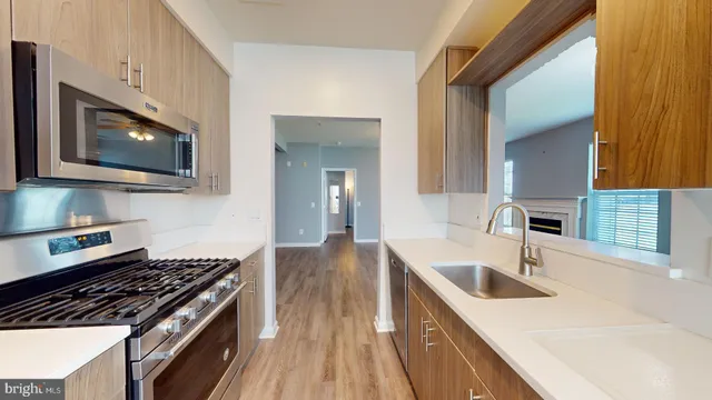 a kitchen with granite countertop a sink a stove top oven and cabinetry