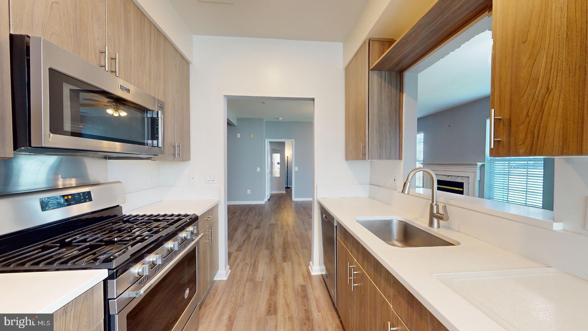 5947 Founders Hill Drive, Unit 103 Alexandria, VA 22310 - Photo 7 of 19 a kitchen with granite countertop a sink a stove top oven and cabinetry