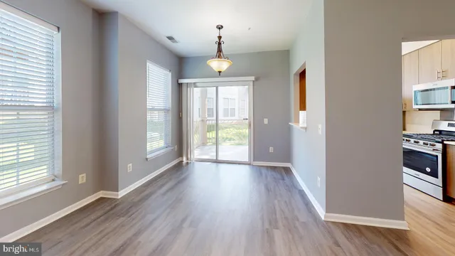an empty room with wooden floor chandelier and windows