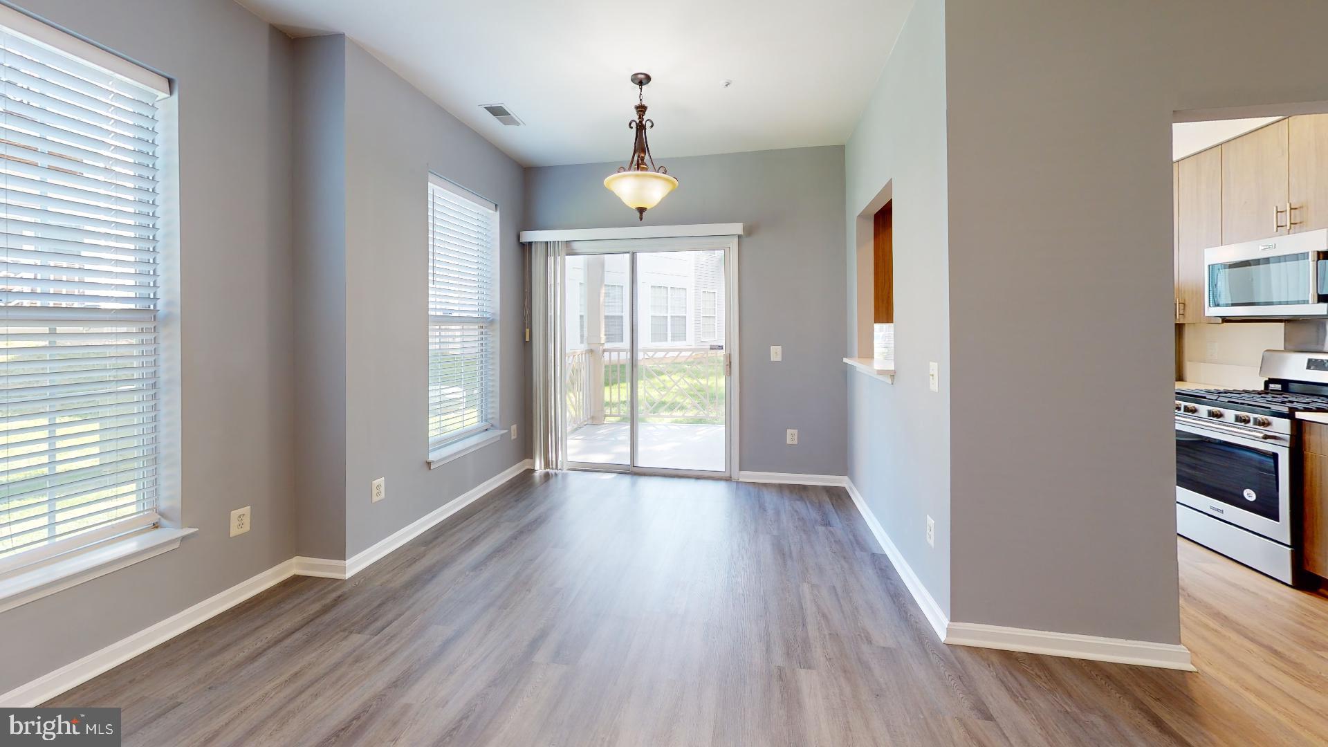 5947 Founders Hill Drive, Unit 103 Alexandria, VA 22310 - Photo 9 of 19 an empty room with wooden floor chandelier and windows