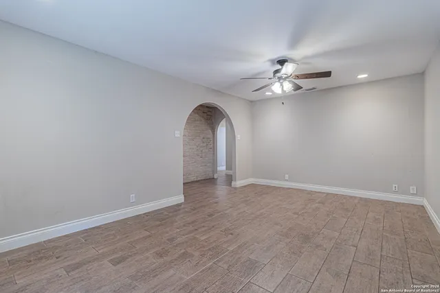 wooden floor in an empty room with a chandelier fan