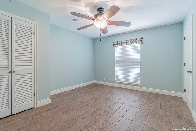 an empty room with a chandelier fan and windows