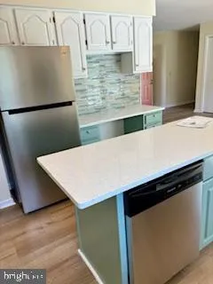 a kitchen with stainless steel appliances a refrigerator a sink a stove and white cabinets