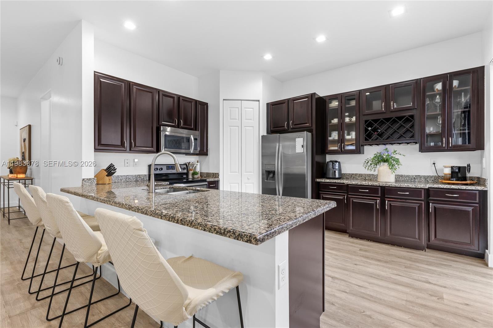 9094 Southwest 36th Street Miramar, FL 33025 - Photo 13 of 50 a kitchen with stainless steel appliances granite countertop a stove top oven a sink dishwasher a dining table and chairs with wooden floor