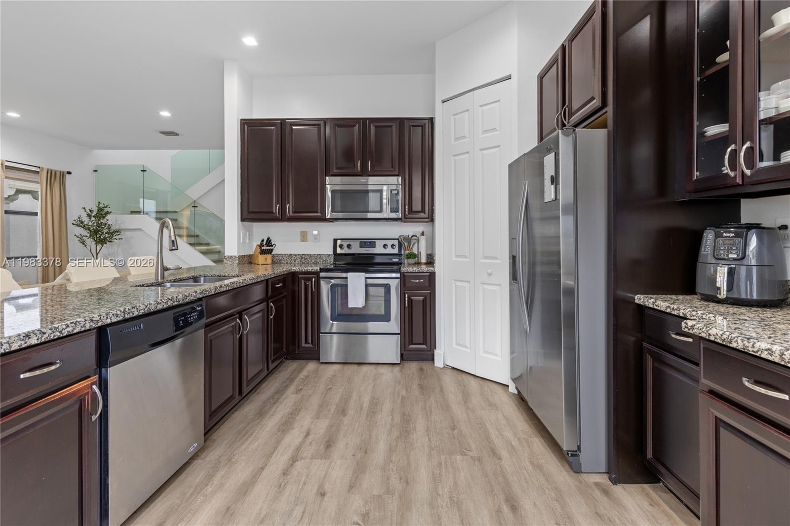 9094 Southwest 36th Street Miramar, FL 33025 - Photo 14 of 50 a kitchen with stainless steel appliances granite countertop wooden cabinets a refrigerator a sink a stove and a wooden floors
