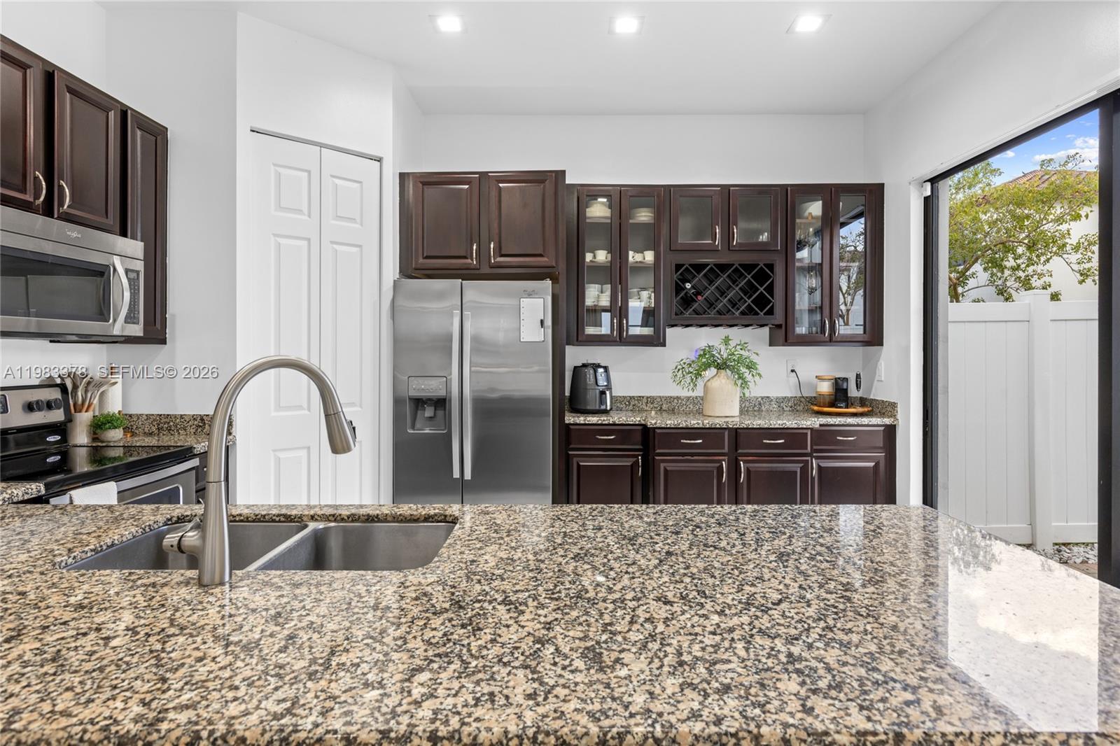 9094 Southwest 36th Street Miramar, FL 33025 - Photo 16 of 50 a kitchen with stainless steel appliances granite countertop a refrigerator a stove top oven a sink a dining table and chairs with wooden floor