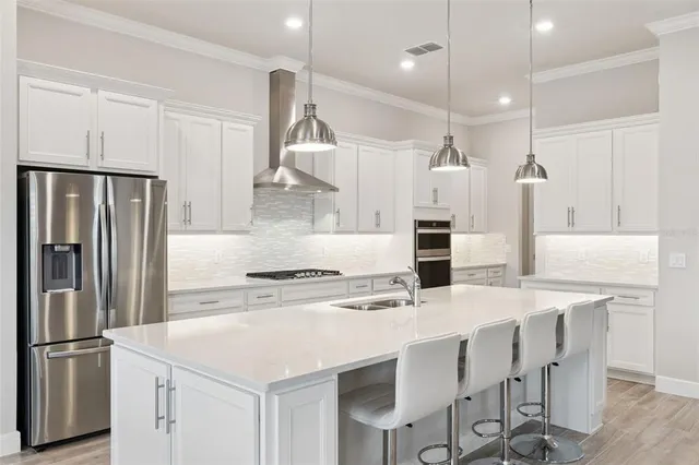 a kitchen with kitchen island a stove a refrigerator a sink and chairs