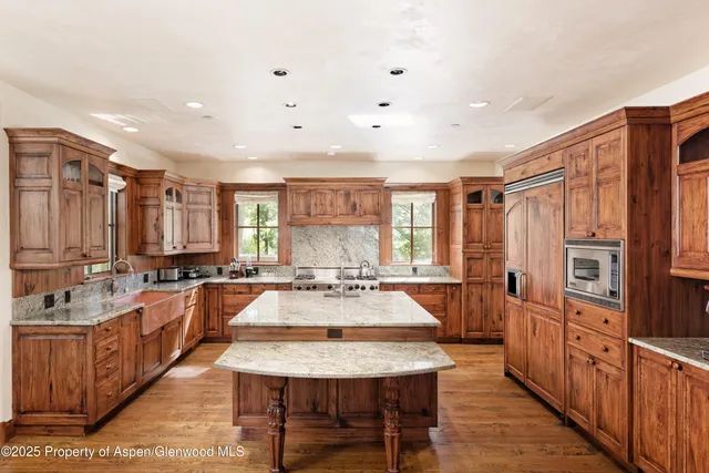 a large kitchen with lots of counter space a sink refrigerator and cabinets