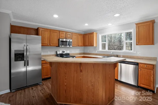 a kitchen with stainless steel appliances granite countertop a refrigerator a sink a stove a microwave and island