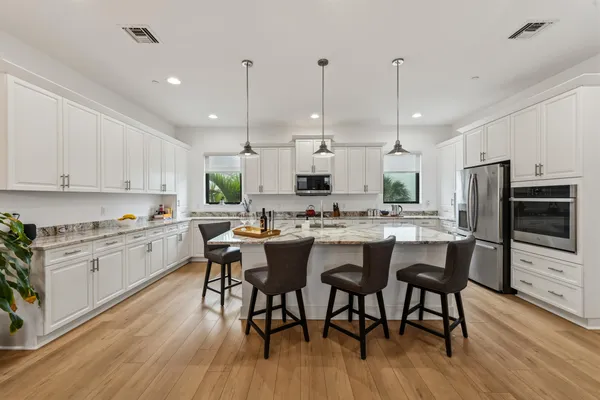 a kitchen with stainless steel appliances kitchen island granite countertop a table chairs stove and white cabinets