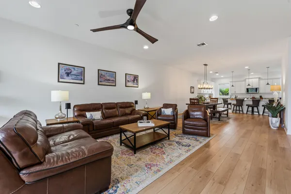 a living room with furniture kitchen view and a wooden floor