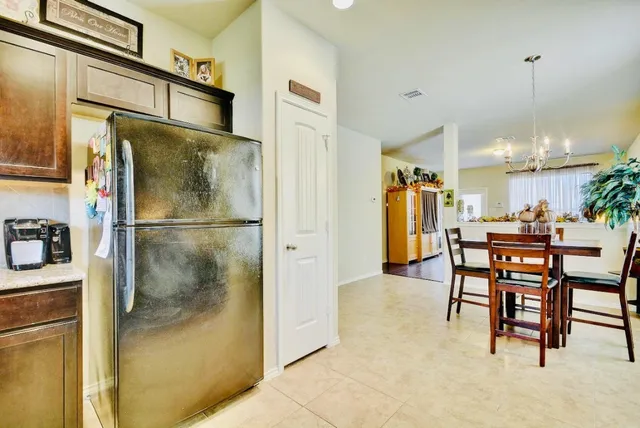 a kitchen with stainless steel appliances kitchen island granite countertop dining table chairs and a refrigerator