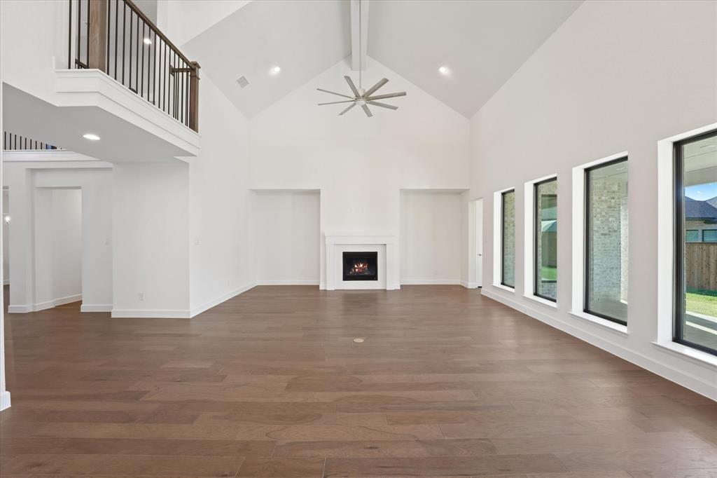 4626 Rillstone Road Midlothian, TX 76065 - Photo 6 of 40 Unfurnished living room featuring beamed ceiling, high vaulted ceiling, a lit fireplace, dark wood-type flooring, and a ceiling fan