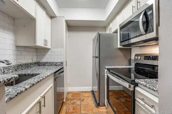 a kitchen with stainless steel appliances granite countertop a refrigerator and a stove