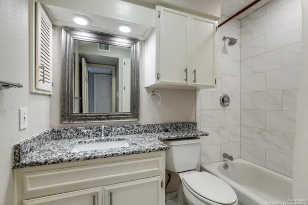 a bathroom with a granite countertop sink toilet and shower