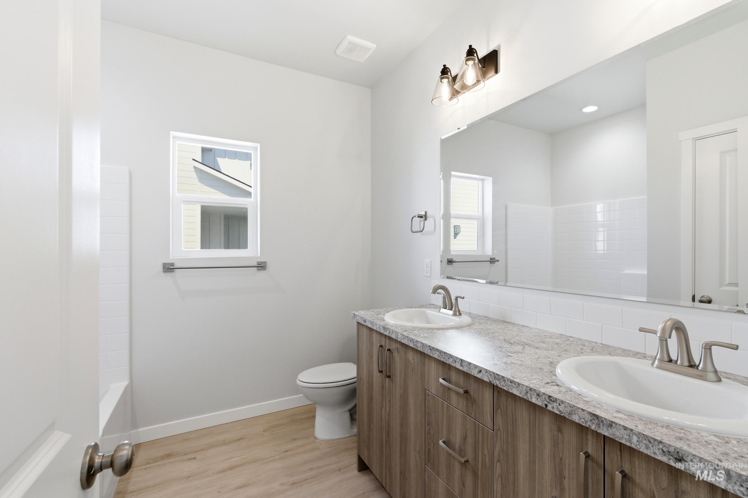 13663 Redway Court Caldwell, ID 83607 - Photo 21 of 32 Dual vanity with light-tone wood-finish cabinetry, speckled countertop, and undermount sinks