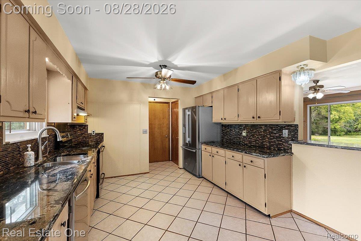 15250 34 Mile Road Armada, MI 48005 - Photo 27 of 49 Kitchen featuring neutral cabinetry, dark patterned countertops, a coordinating backsplash, and tile flooring
