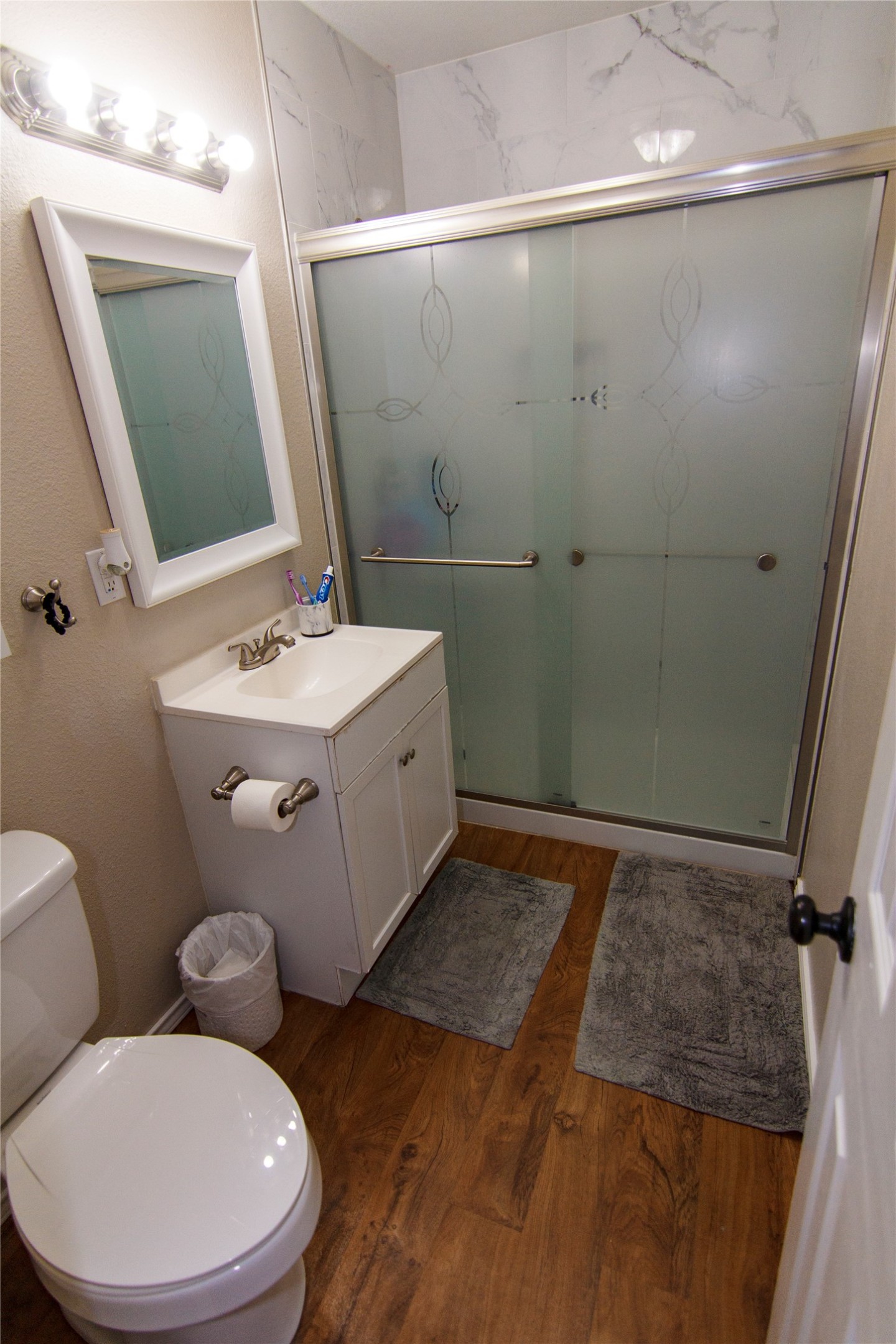 200 Keanahalululu Lane, Unit R Bastrop, TX 78602 - Photo 17 of 32 Bathroom with a shower stall, vanity, and dark wood-style floors