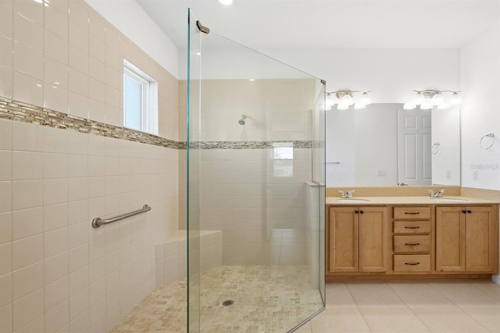 10374 Southwest 96th Street Ocala, FL 34481 - Photo 18 of 29 a bathroom with a granite countertop sink a mirror and a shower