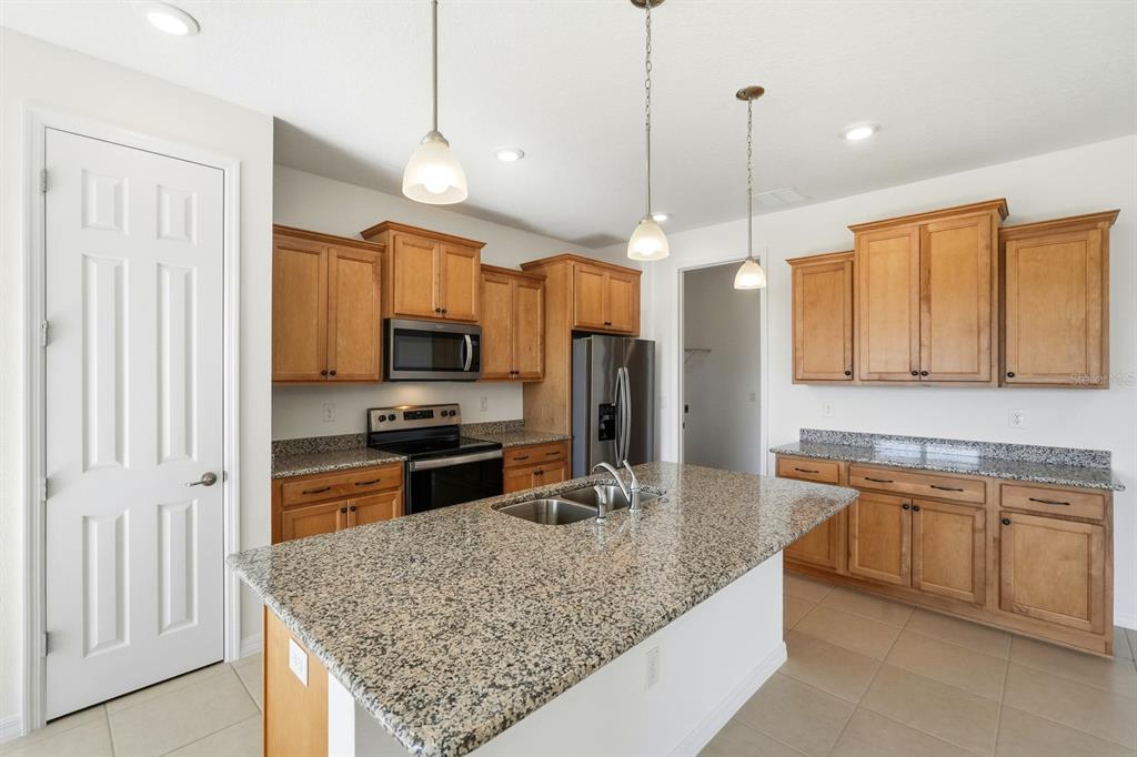 10374 Southwest 96th Street Ocala, FL 34481 - Photo 7 of 29 a kitchen with stainless steel appliances granite countertop wooden cabinets a sink a stove a oven a dining table and chairs