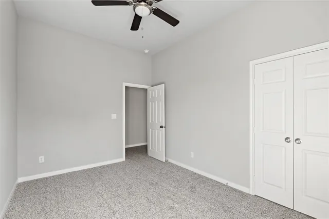 an empty room with a ceiling fan and a window