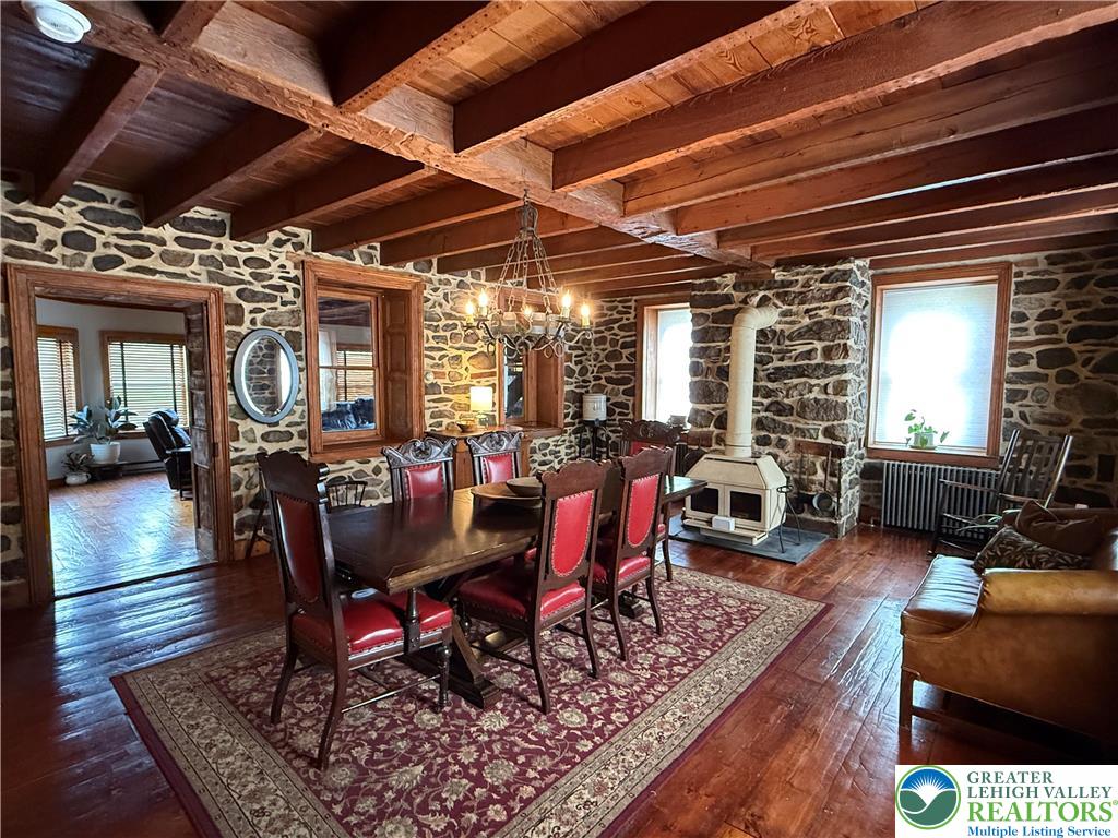 940 Jacktown Road Bangor, PA 18013 - Photo 9 of 33 Exposed wood beams crown this spacious dining area, complementing rustic stone walls and polished hardwood flooring.