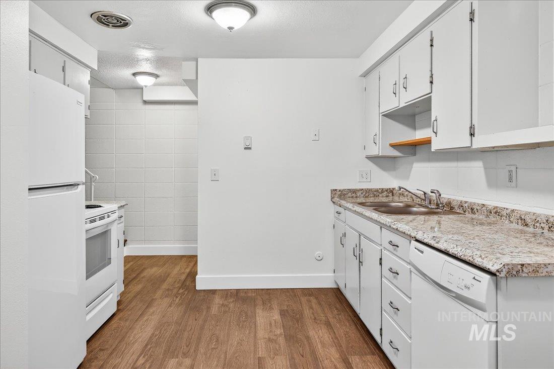 824 South Curtis Road Boise, ID 83705 - Photo 11 of 19 Kitchen with white appliances, light wood-style flooring, light countertops, white cabinetry, and a textured ceiling