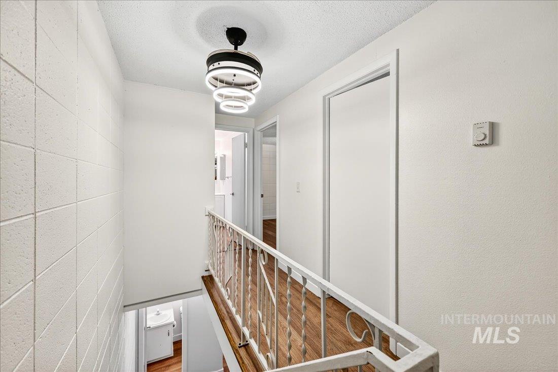824 South Curtis Road Boise, ID 83705 - Photo 13 of 19 Hallway with concrete block wall, a textured ceiling, an upstairs landing, and wood finished floors