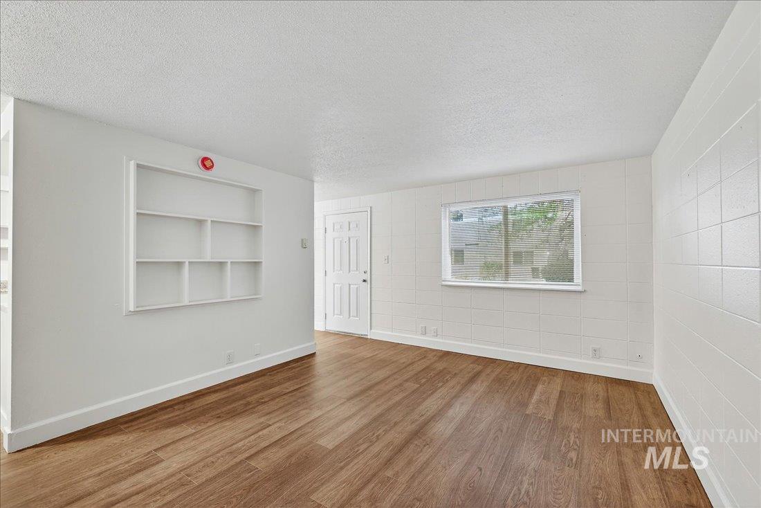 824 South Curtis Road Boise, ID 83705 - Photo 9 of 19 Empty room with wood finished floors, a textured ceiling, and built in shelves