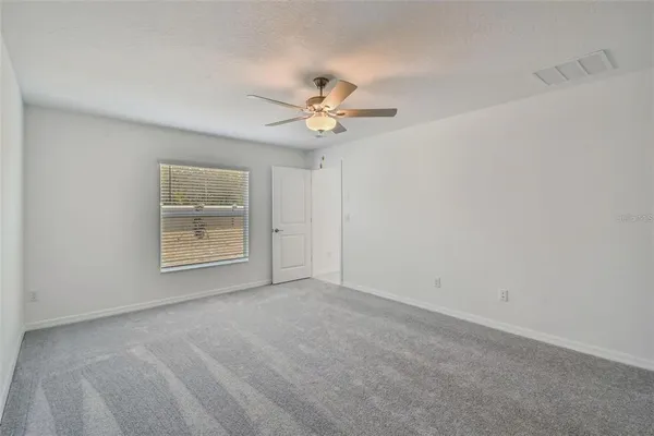 an empty room with windows and fan