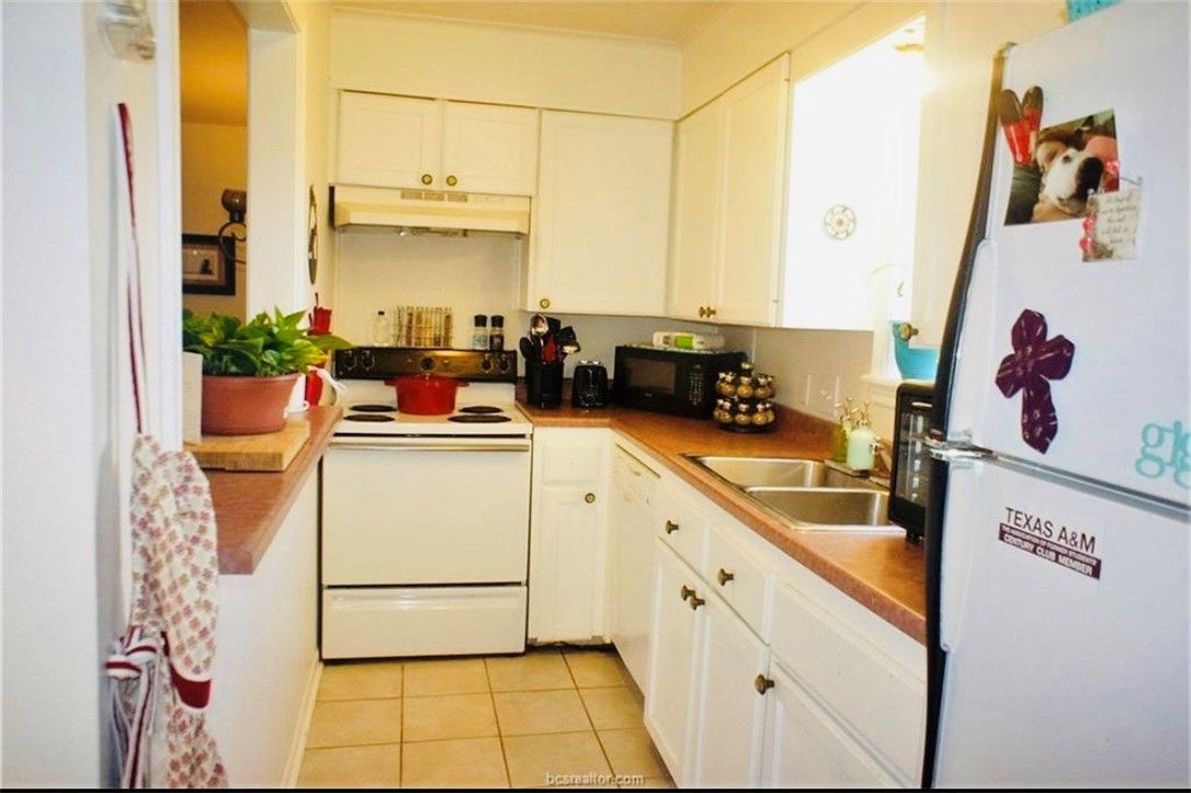 1409 Hawk Tree Drive College Station, TX 77845 - Photo 5 of 12 a kitchen with stainless steel appliances a stove a refrigerator and white cabinets