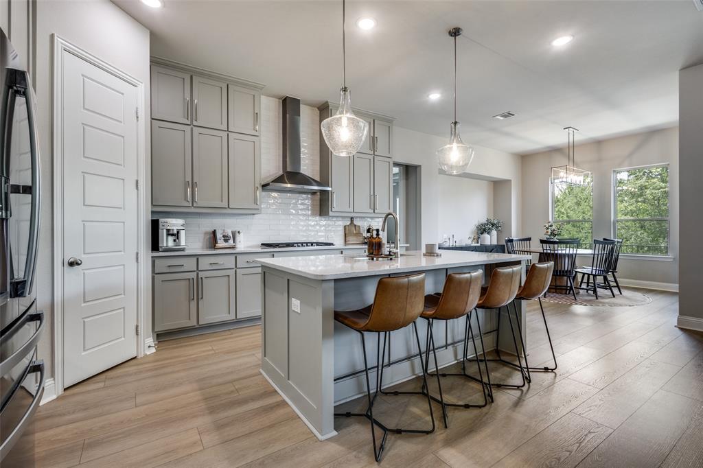 1113 Stone Bridge Pass Gunter, TX 75058 - Photo 11 of 32 a kitchen with stainless steel appliances granite countertop a sink a stove a refrigerator and island with wooden floor